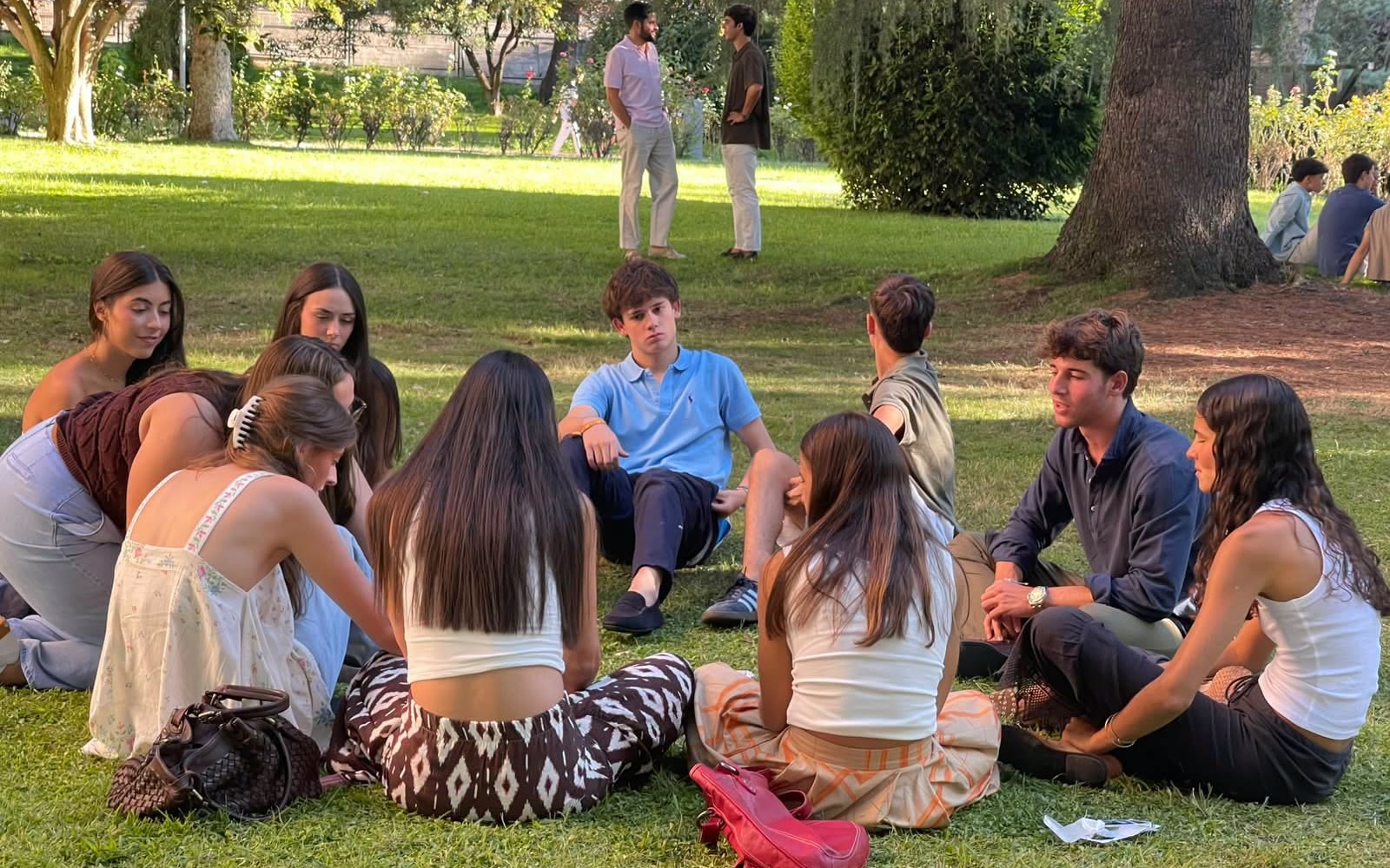 Colegiales y colegialas sentados en círculo en el jardín durante una dinámica de las actividades de integración